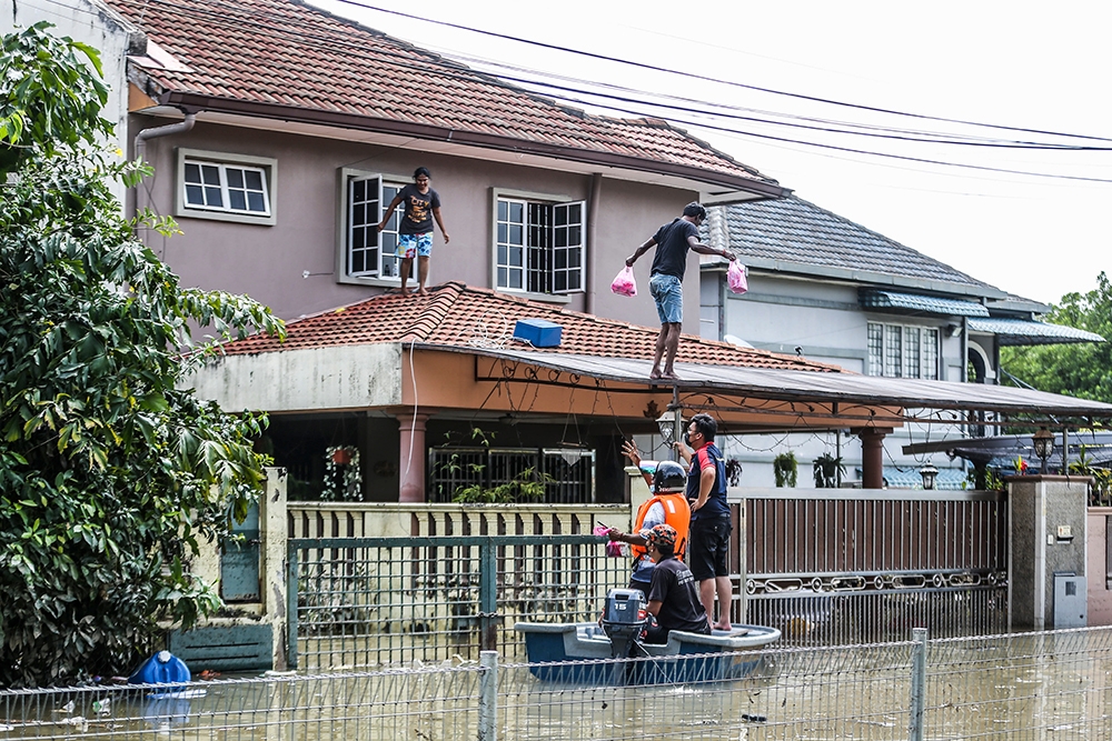 Several flood victims wade through the floods in Taman Sri Muda Section 25 Shah Alam on December 20, 2021. — Picture by Hari Anggara