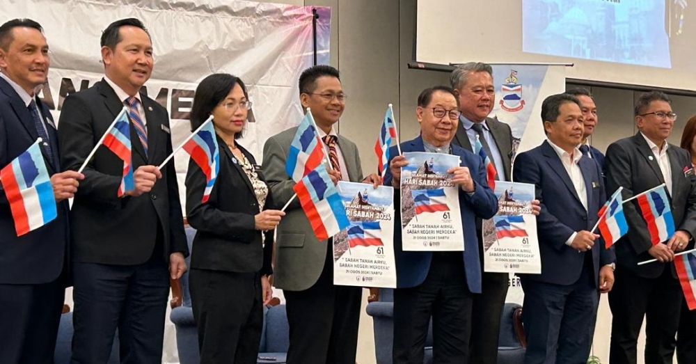Datuk Seri Jeffrey Kitingan (fifth from left) waving the Sabah flag and Sabah Day poster at the press conference. — Borneo Post pic