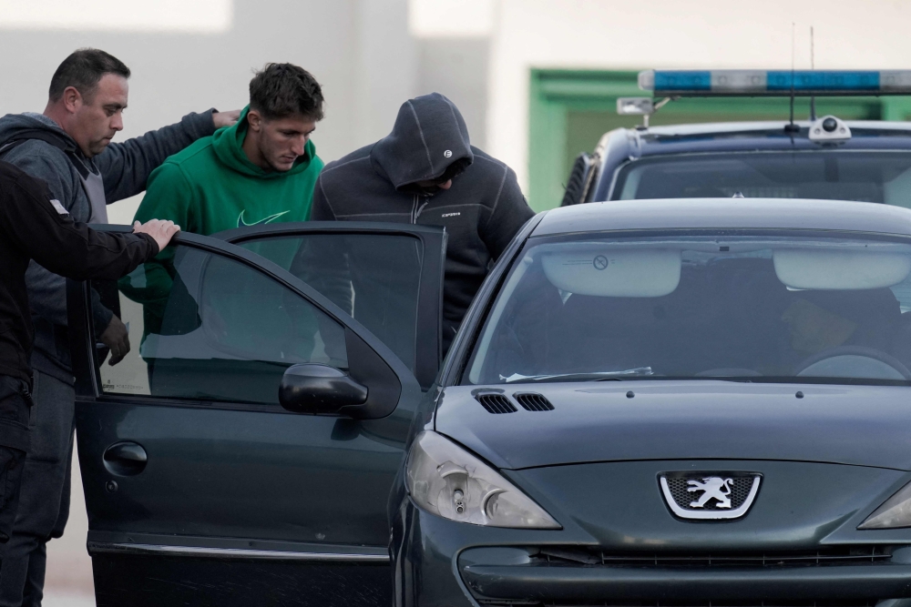 French national rugby players Oscar Jegou (centre) and Hugo Auradou (right) are escorted by members of the Mendoza prison service as they are transferred to house arrest in Mendoza, Argentina, July 17, 2024. — AFP pic