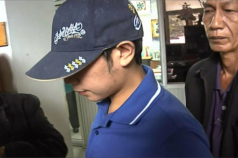 A file photograph show a frame grab from video footage Red Bull heir Vorayuth Yoovidhya (centre) entering Thong Lor police station in Bangkok. — AFP pic