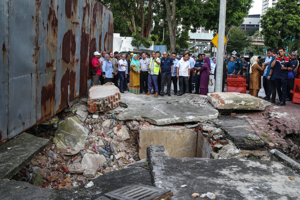 Federal Territories Minister Dr Zaliha Mustafa (in turquoise headscarf) and Communications Minister Fahmi Fadzil inspect the site of a collapsed drain at Jalan Pantai Permai, Kampung Kerinchi in Kuala Lumpur on August 28, 2024. — Picture by Yusof Mat Isa