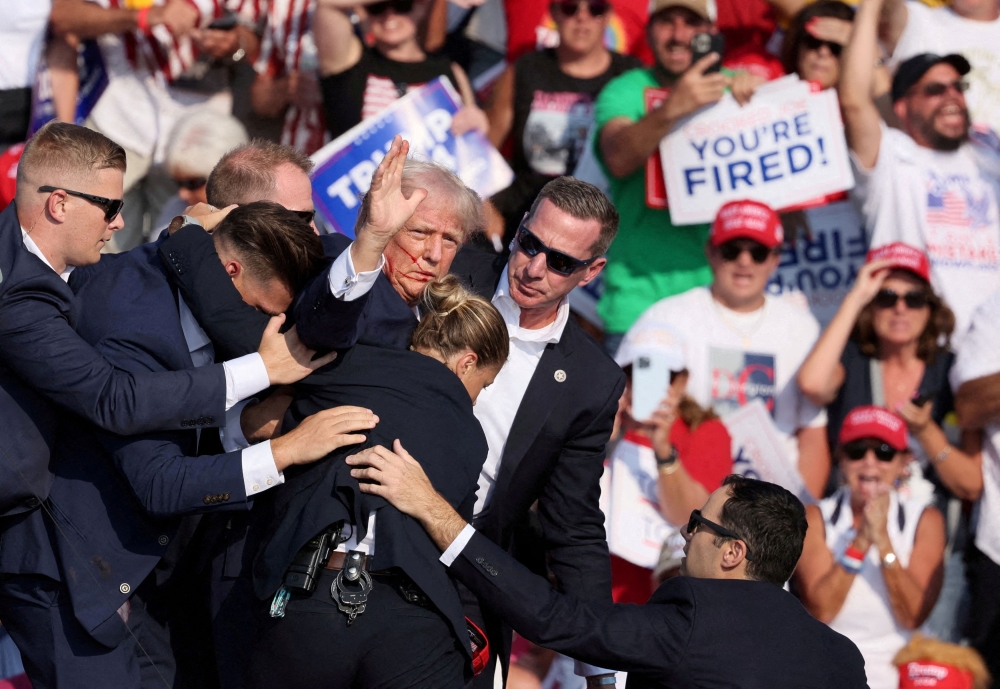 zRepublican presidential candidate and former U.S. President Donald Trump gestures with a bloodied face while he is assisted by U.S. Secret Service personnel after he was shot in the right ear during a campaign rally at the Butler Farm Show in Butler, Pennsylvania, U.S., July 13, 2024. — Reuters pic 