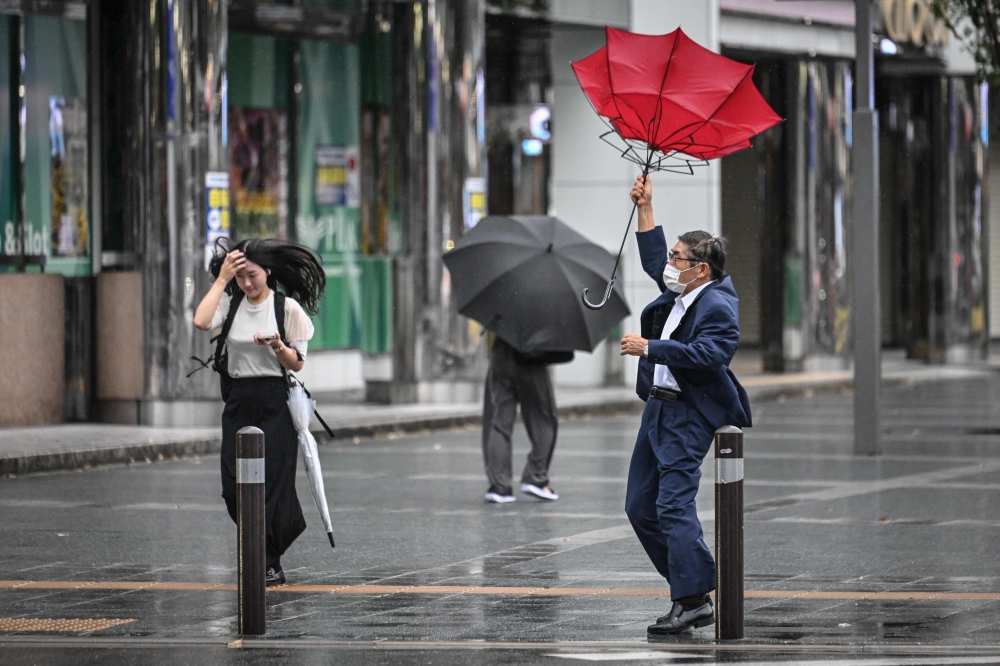 A man holds his umbrella in the wind outside Hakata station in Fukuoka, Japan, on August 29, 2024. Japan prepared on August 28 for its strongest typhoon of the year, with authorities advising tens of thousands of people to evacuate and issuing the highest warning level for wind and storm surges on the main southern island of Kyushu. — AFP pic