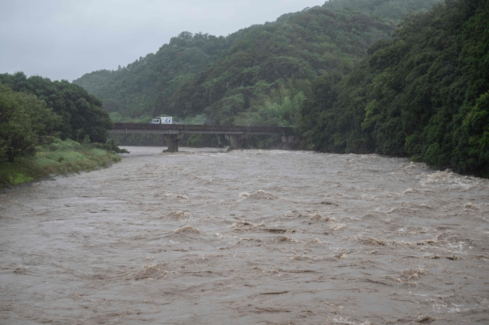 A general view shows the swollen Tsubusa river due to heavy rain brought by Typhoon Shanshan in Usa, Oita prefecture on August 29, 2024. Typhoon Shanshan hit Japan with full force on August 29, injuring dozens as howling winds smashed windows and blew tiles off houses while torrential rains turned rivers into raging torrents. — AFP pic