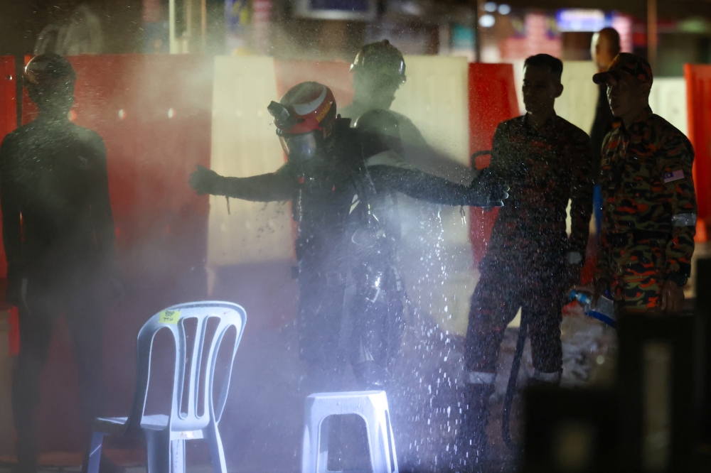 The two divers from the Fire and Rescue Department’s Water Rescue Team going through a decontamination process after diving at the site earlier today. — Bernama pic