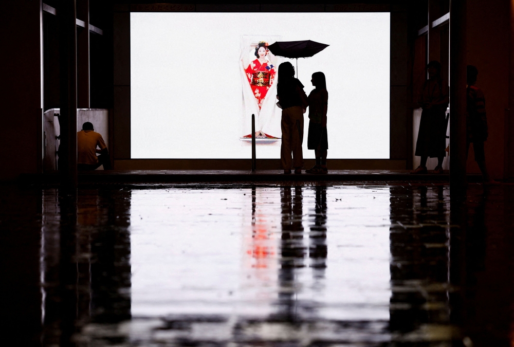 Passersby with an umbrella stand in rain and winds as Typhoon Shanshan approaches, at Hakata Station in Fukuoka, Japan, on August 29, 2024. — Reuters pic