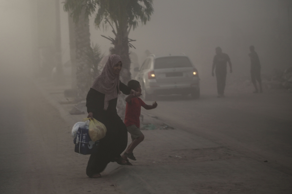 Palestinians find their way amid the dust and smoke after Israeli troops targeted a building in the Nuseirat refugee camp in the central Gaza Strip on August 22, 2024. — AFP pic