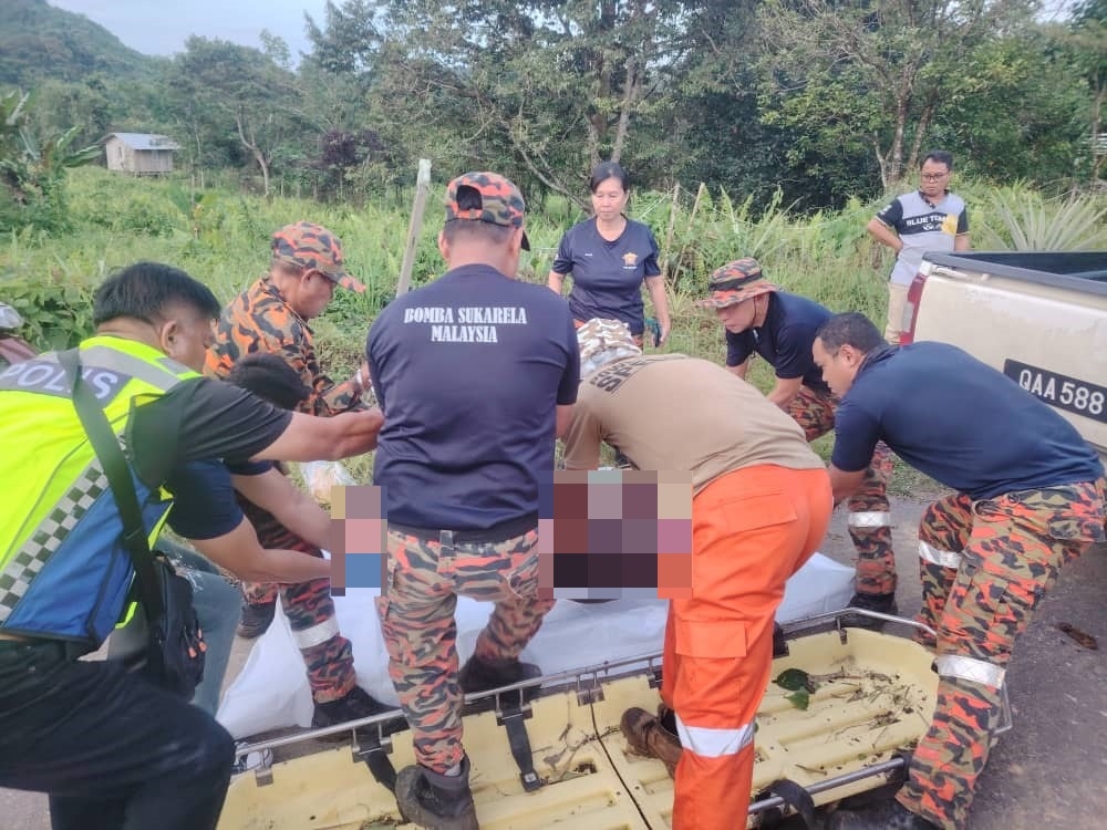 Firefighters and police personnel prepare the victim’s body for transportation. — The Borneo Post pic 