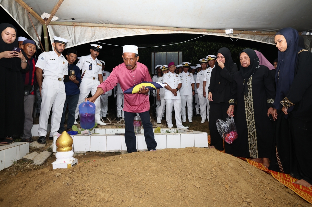 Hermansa Senda, the father of Class I Soldier (LK) PLM Arman San Hermansa sprinkles rose water on the grave of his son who was buried at the Kampung Terusan Islamic Cemetery in Lahad Datu August 30, 2024. — Bernama pic