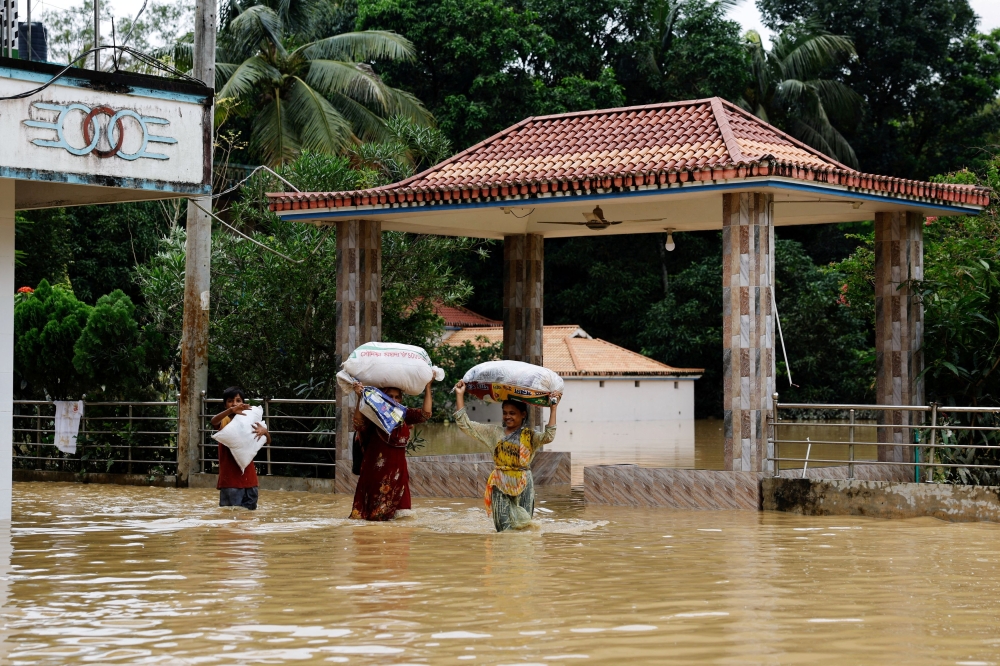 People carrying sacks, wade through flood water, amid severe flooding in the Fazilpur area of Feni, Bangladesh, August 26, 2024. — Reuters pic  