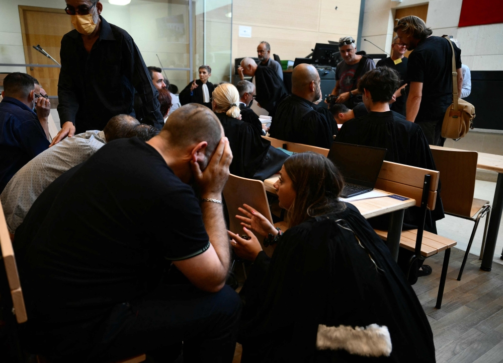 Co-defendants speak with a lawyer at the courthouse during the trial of a man accused of drugging his wife for nearly ten years and inviting strangers to rape her at their home in Mazan, a small town in the south of France, in Avignon, on September 2, 2024. — AFP pic