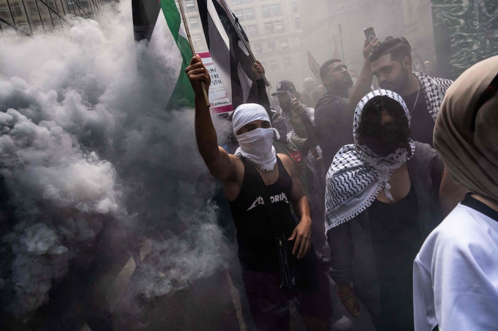 People walk through smoke as they attend a protest in support of the war in Gaza, on Labor Day on September 2, 2024 in New York City. — AFP pic