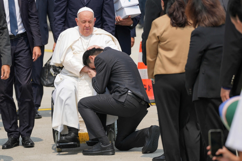 A man kneels before Pope Francis upon his arrival for a farewell at Jakarta’s Soekarno-Hatta International Airport ahead of his departure to Papua New Guinea’s capital Port Moresby on September 6, 2024. — AFP pic 