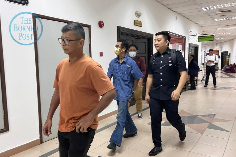 A police officer escorts (from left) Goh, Hafiz and Irman out of the courtroom at the end of the proceedings. — BORNEO POST