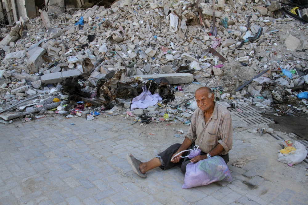 A Palestinian man sits in front of rubble in the Jabalia refugee camp in the northern Gaza Strip at the site where a makeshift pastry shop was hit by an Israeli strike on September 2, 2024. — Reuters pic