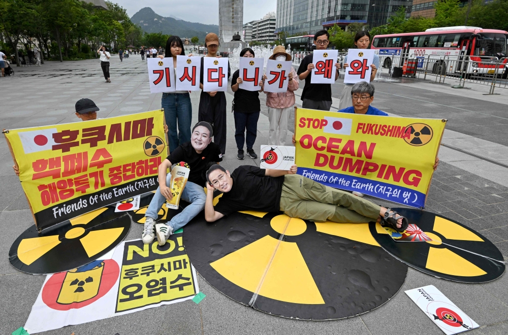 South Korean environmental activists wearing masks of Japan's Prime Minister Fumio Kishida (right) and South Korea's President Yoon Suk Yeol (left) take part in a protest against Kishida's planned visit and Japan's discharge of Fukushima contaminated water, at Gwanghwamun Square in Seoul on September 5, 2024. — AFP pic