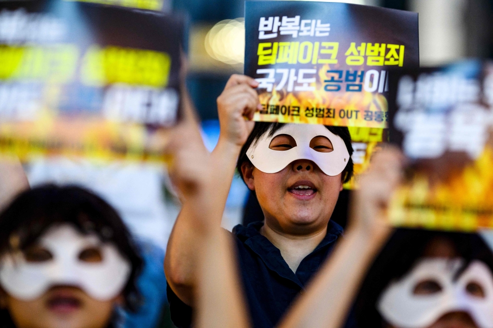 Activists wearing eye masks, hold posters reading 'Repeated deepfake sex crimes, the state is an accomplice too?' during a protest against deepfake porn in Seoul on August 30, 2024. — AFP pic