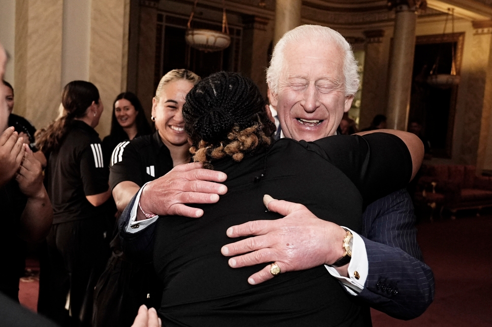 Britain's King Charles III reacts as he is hugged by members of New Zealand's Black Ferns rugby union team, at Buckingham Palace in central London on September 11, 2024. — AFP pic