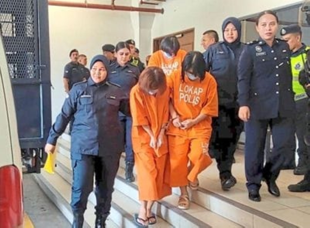Three of the 10 accused are escorted out of the court lockup in Kota Kinabalu, Sabah. — The Borneo Post pic