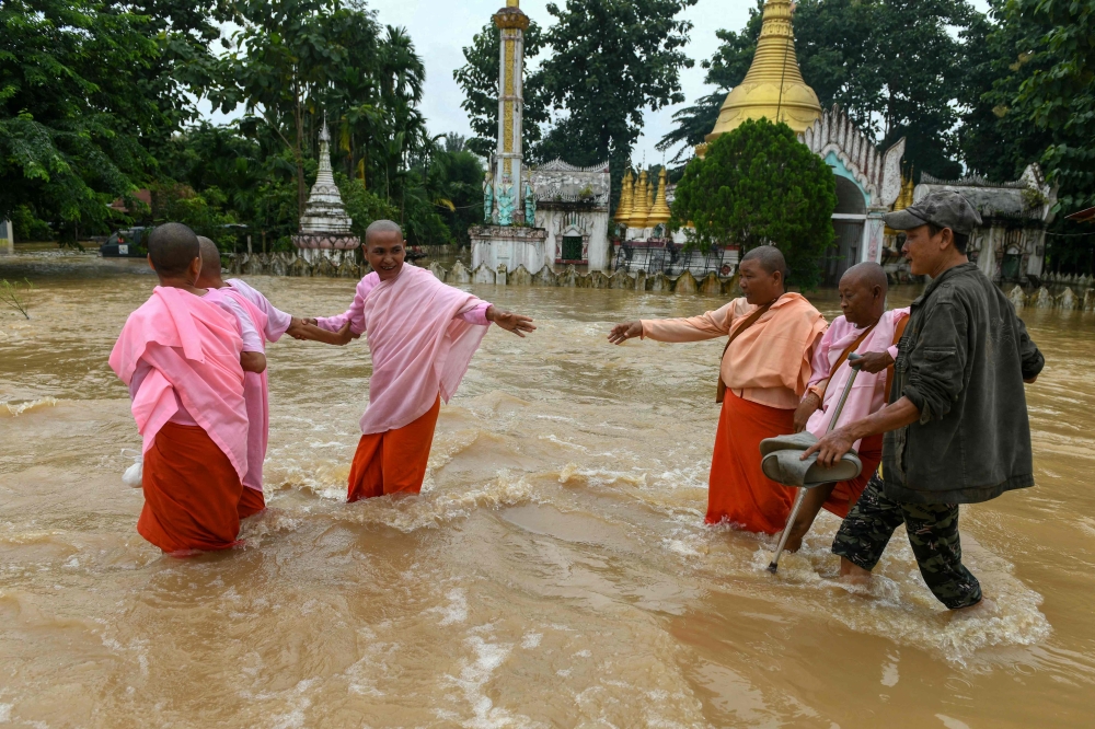 Buddhist nuns walk through flood waters by a temple in Taungoo, Myanmar's Bago region on September 14, 2024, following heavy rains in the aftermath of Typhoon Yagi. — AFP pic