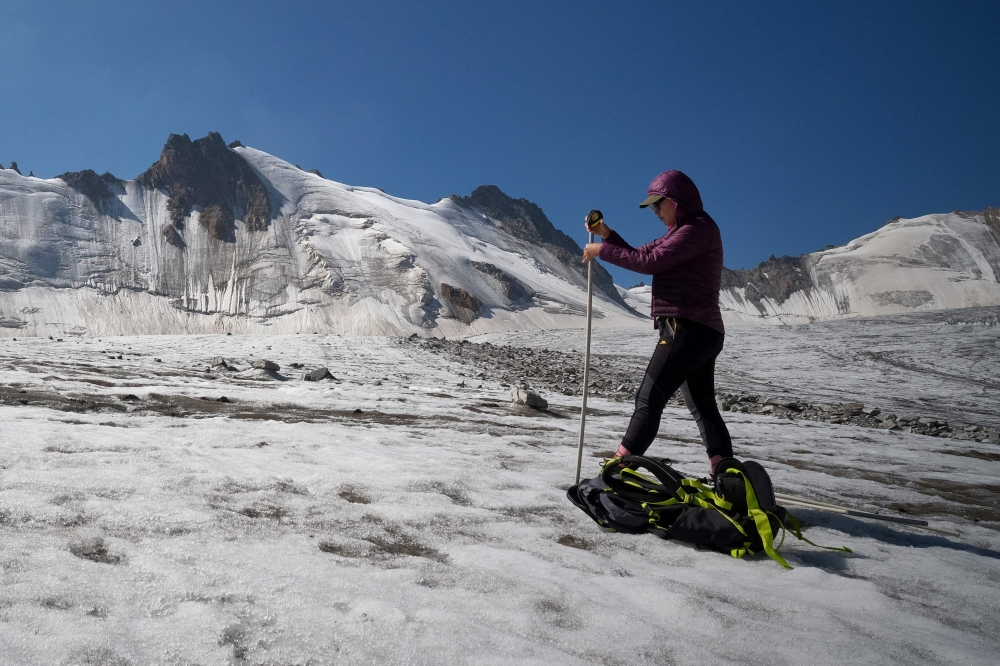 Glaciologist Gulbara Omorova takes measurements of a glacier using an ablation stake in the Tian Shan mountain range on July 8, 2024. — AFP pic