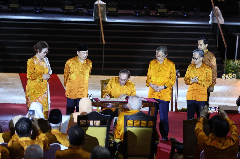Sabah chief minister Datuk Seri Hajiji Noor (second left) looks at Prime Minister Datuk SerI Anwar Ibrahim signing the Malaysia Day 2024 special book. — Bernama pic