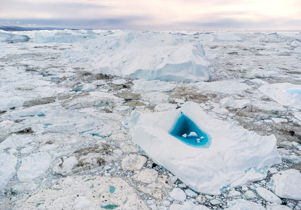 Picture taken on June 29, 2022 with a drone shows turquoise water in a large melt hole on the top of an iceberg in the Disko Bay, Ilulissat, western Greenland. — AFP pic