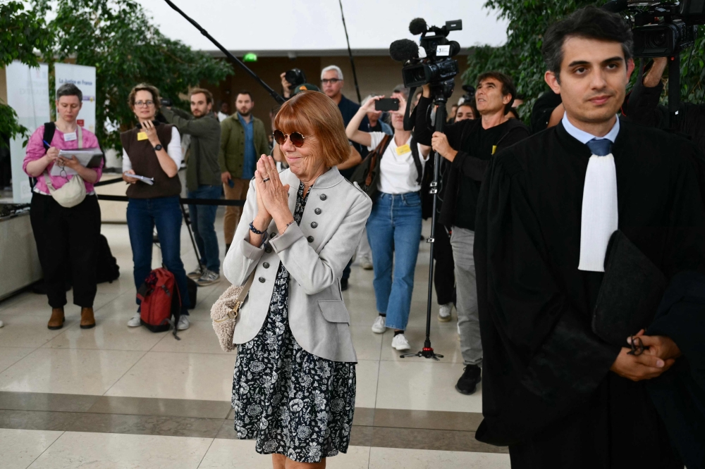 Gisele Pelicot acknowledges applause flanked by her lawyers Stephane Babonneau (R) as she exits the courtroom at the Avignon courthouse during the trial of her former partner Dominique Pelicot accused of drugging her for nearly ten years and inviting strangers to rape her at their home in Mazan, a small town in the south of France, in Avignon, on September 17, 2024. — AFP pic