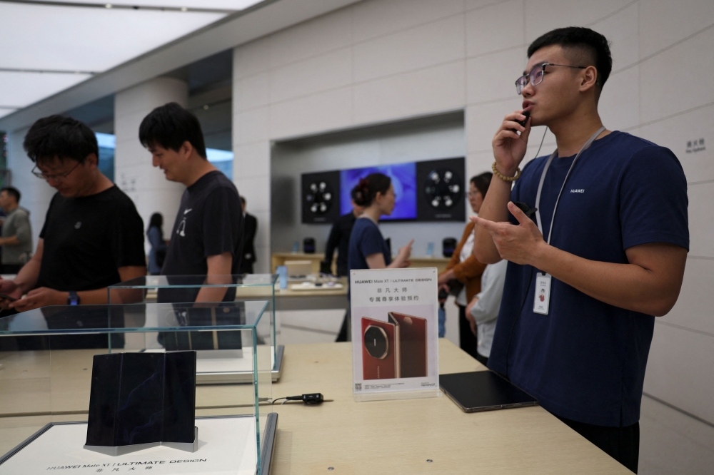 A staff member introduces Huawei Mate XT as the tri-foldable smartphone goes on sale at a Huawei flagship store in Beijing September 20, 2024. — Reuters pic  