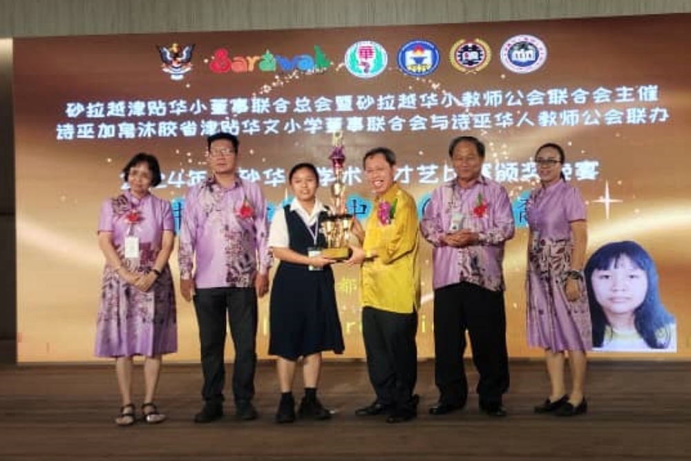 Dr Sim (third right) presents a trophy to a calligraphy winner (non-Chinese category) Jocelyn Lirek Richard. — The Borneo Post pic
