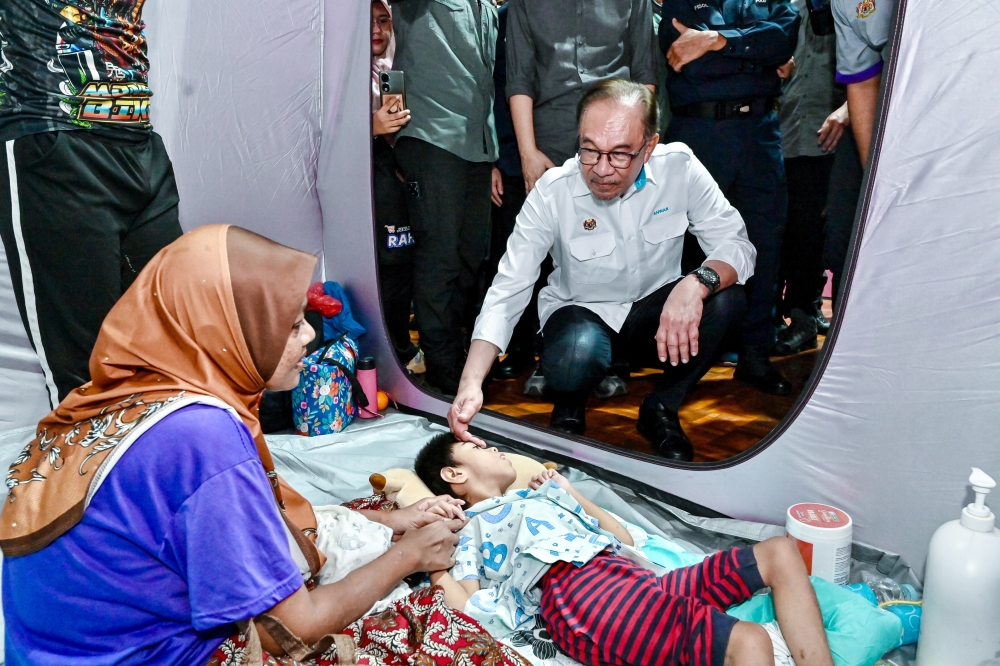 Prime Minister Datuk Seri Anwar Ibrahim visits Mohamad Afiq Ramadan, nine, who was bedridden due to convulsions since birth when he visited the flood victims at the Suka Menanti Stadium temporary evacuation centre in Alor Setar September 21, 2024. — Bernama pic