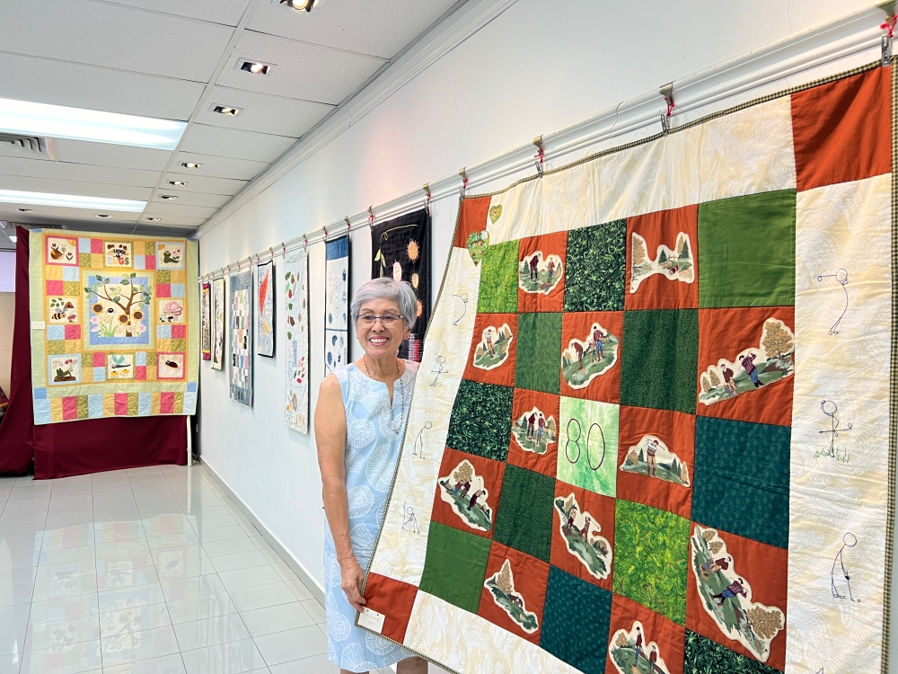 Janie Yap holding a quilt she made for her husband’s 80th birthday featuring his hobby, golf. — Picture by Opalyn Mok