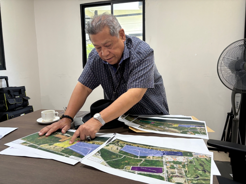 Pandikar showing the map of Tanjung Aru beach and the proposed plans for its redevelopment which includes improved traffic planning — Picture by Julia Chan