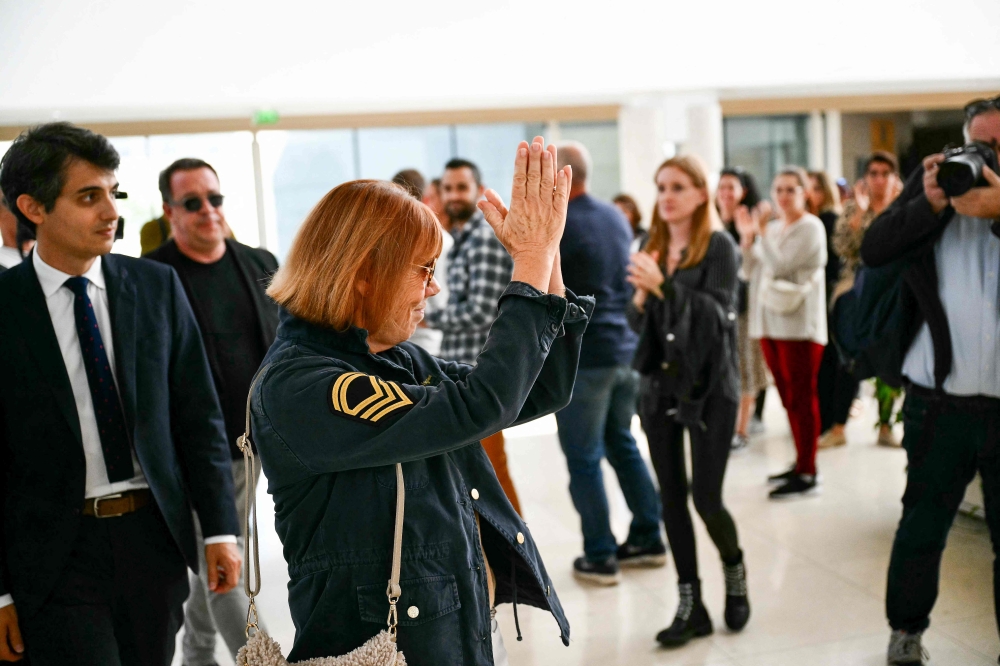 Gisele Pelicot, flanked by her lawyer Stephane Babonneau (left), returns the public applause as she leaves the Avignon courthouse during the trial of her former husband Dominique Pelicot accused of conducting a 10-year-long mass drug-rape against her at their home in Mazan, south France, on September 23, 2024. — AFP pic