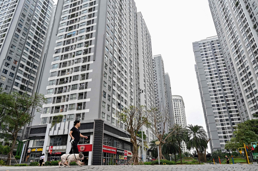 A woman walks her dog in a residential complex in Hanoi on September 25, 2024. — AFP pic