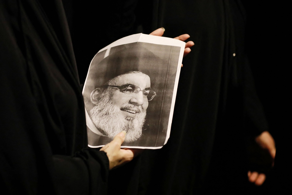 Demonstrators hold pictures of Hassan Nasrallah, late leader of the Lebanese group Hezbollah, during a protest vigil near the suspension bridge leading to Baghdad's Green Zone on September 28, 2024. — AFP pic