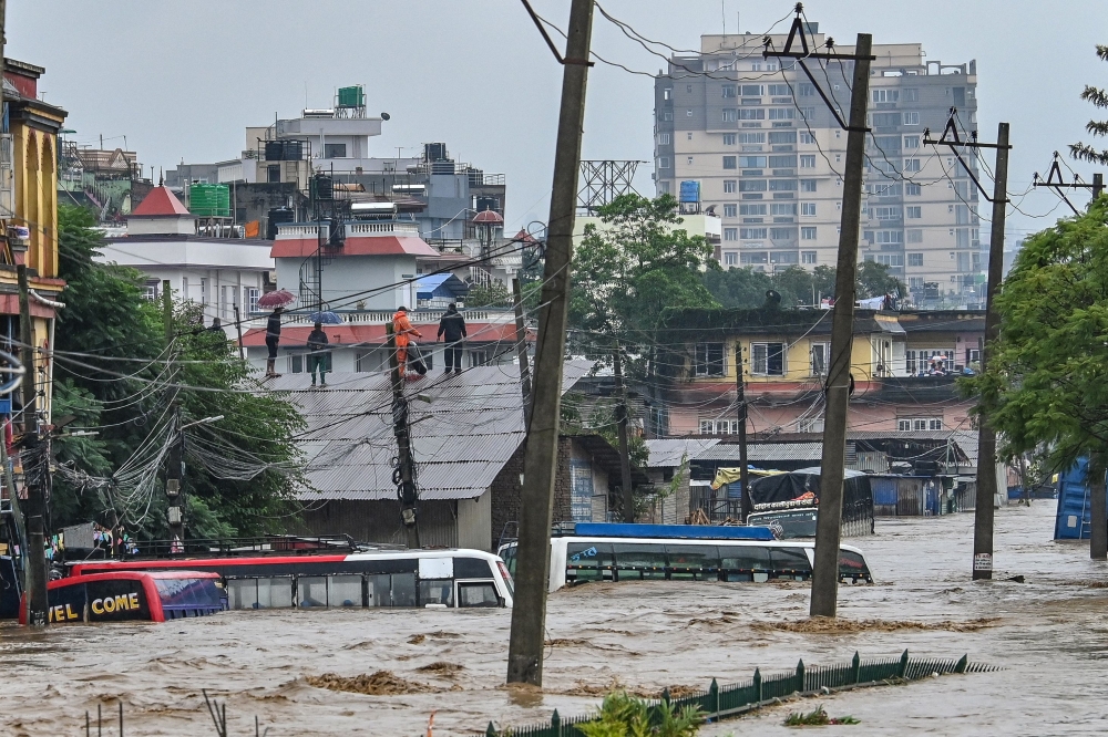 Residents climb over a rooftop as their neighbourhood submerged in flood waters after the Bagmati River overflowed following heavy monsoon rains in Kathmandu September 28, 2024. — AFP pic