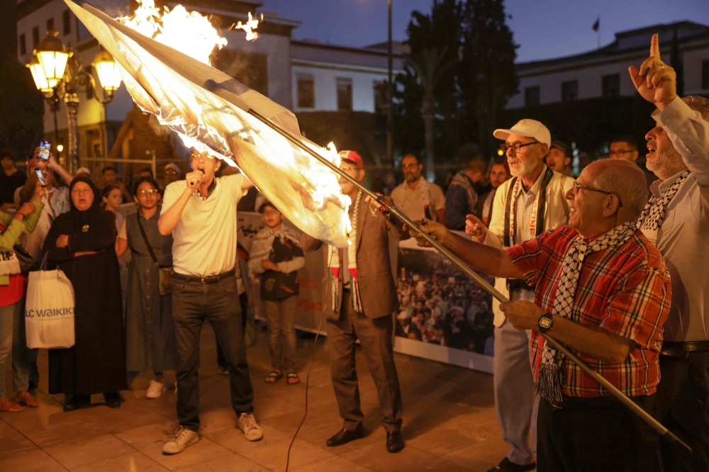 Demonstrators burn an Israeli flag in front of the parliament building in Rabat on September 28, 2024. — AFP pic