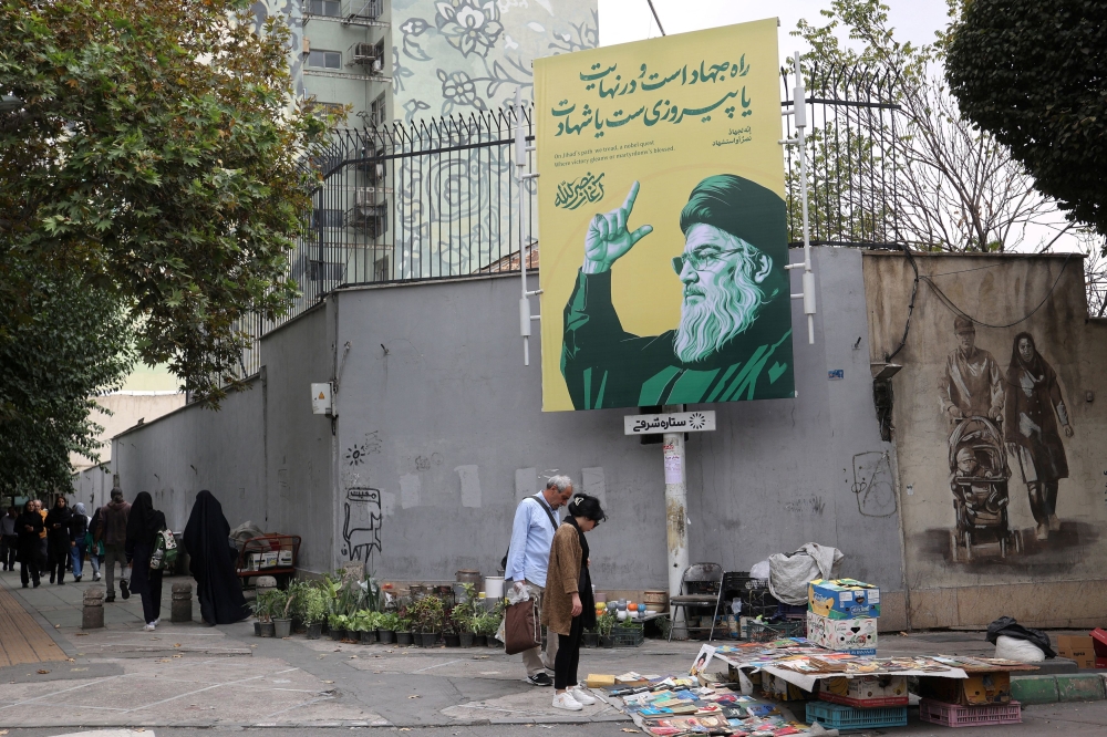 People stand next to a banner with a picture of the late Lebanon’s Hezbollah leader Hassan Nasrallah, in a street in Tehran, Iran September 29, 2024. — Majid Asgaripour/WANA (West Asia News Agency) pic via Reuters 