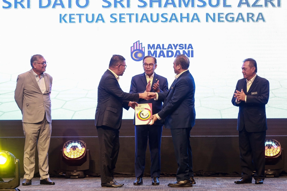 Prime Minister Datuk Seri Anwar Ibrahim looks on as Home Minister Datuk Seri Saifuddin Nasution Ismail hands over a copy of the action plan to Chief Secretary to the Government Tan Sri Shamsul Azri Abu Bakar during the launch of the Malaysia Action Plan on Preventing and Countering Violent Extremism in Putrajaya September 30, 2024. — Picture by Sayuti Zainudin