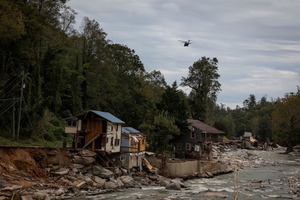 A helicopter flies near damaged buildings following the passing of Hurricane Helene, in Bat Cave, North Carolina, September 30, 2024. — Reuters pic
