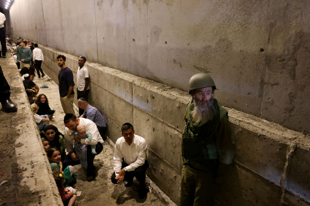 People take shelter during an air raid siren after Iran fired a salvo of ballistic missiles, amid cross-border hostilities between Hezbollah and Israel, in central Israel yesterday. — Reuters pic