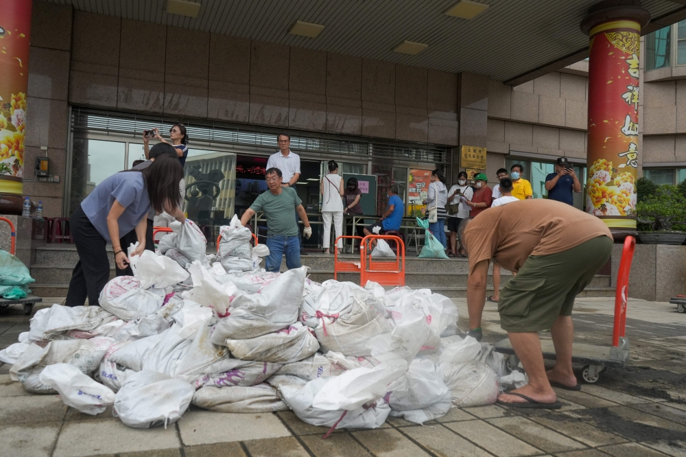 People carry sand bags from city government district offices for distribution in Kaohsiung as super typhoon Krathon moved towards Taiwan. — AFP pic