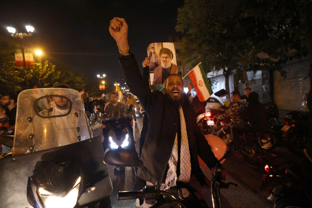 Demonstrators celebrate during a rally outside the British Embassy in Tehran on October 1, 2024, after Iran fired a barrage of missiles into Israel in response to the killing of Hezbollah leader Hassan Nasrallah and other Iranian-backed militias. — AFP pic