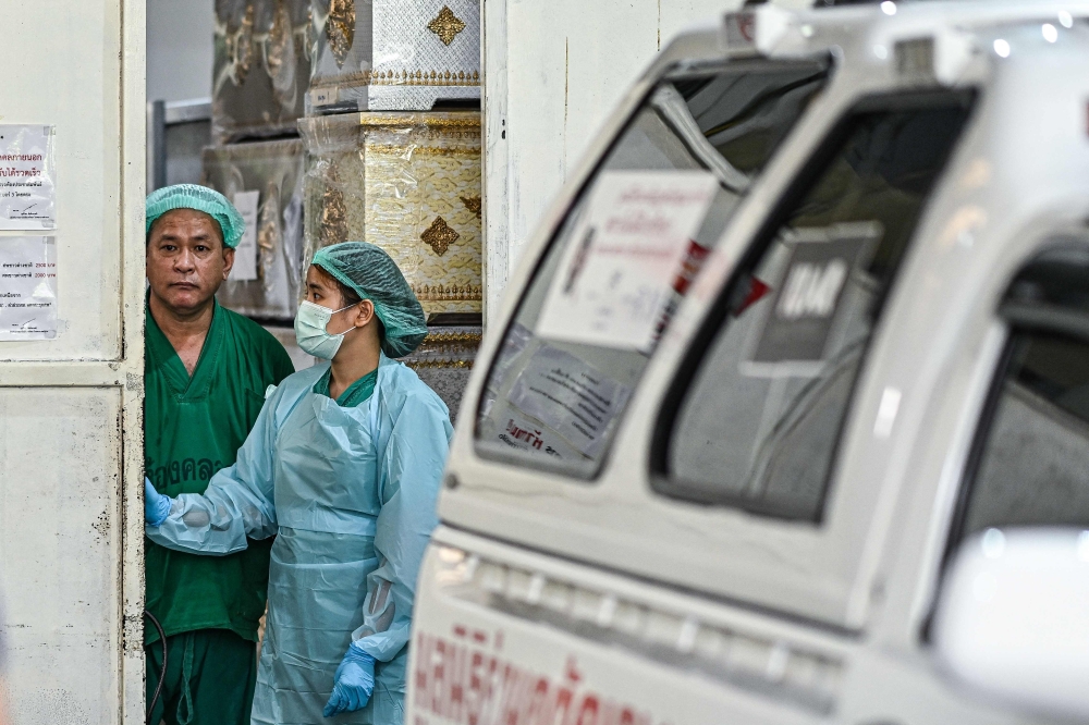 Medical staff look out as they wait to transfer the coffins of victims outside the forensic institute at the police hospital in Bangkok, on October 2, 2024. A devastating fire on a Thai school bus killed at least 23 people, police said on October 1, after rescuers pulled children's bodies from the charred wreckage of the vehicle. — AFP pic