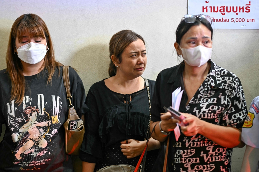 Relatives react as an ambulance carrying the remains of victims of a deadly school bus fire leave the forensic institute at the Police General Hospital in Bangkok on October 2, 2024. — AFP pic