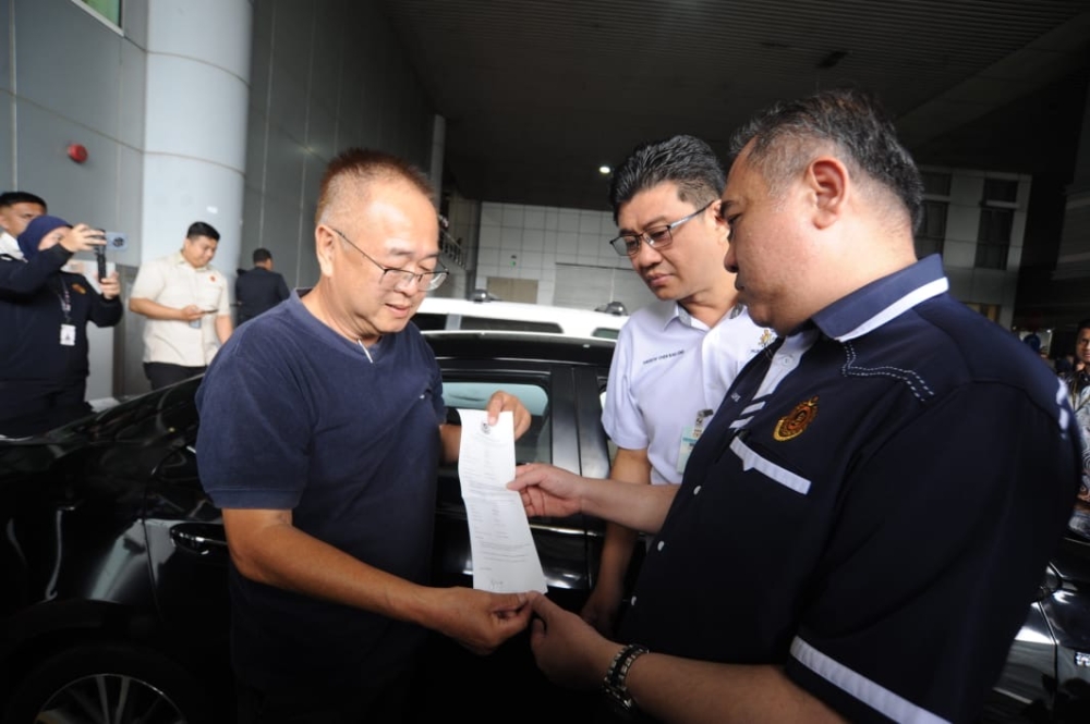 Transport Minister Anthony Loke (right) inspects a warning notice issued to a Singaporean motorist who has yet to apply for the Malaysian Vehicle Entry Permit (VEP) at the Bangunan Sultan Iskandar Customs, Immigration and Quarantine Complex  in Johor Baru on October 3, 2024. — Picture by Ben Tan