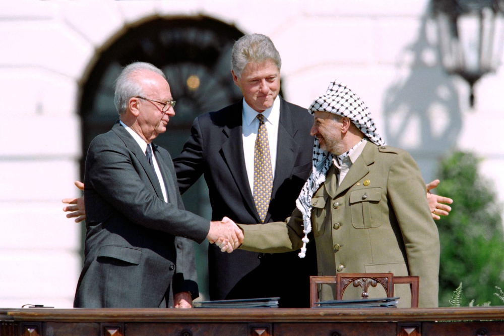 US President Bill Clinton stands between PLO leader Yasser Arafat and Israeli Prime Minister Yitzahk Rabin as they shake hands for the first time, on September 13, 1993 at the White House in Washington DC, after signing the historic Israel-PLO Oslo Accords on Palestinian autonomy in the occupied territories. — AFP pic 
