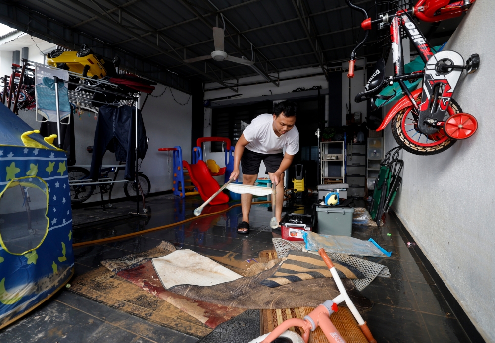 Nasrun Nasyaat Roslan, 29, cleans his house after flash floods hit in Taman Saujana Aman, Kuala Selangor, October 4, 2024. — Bernama pic 
