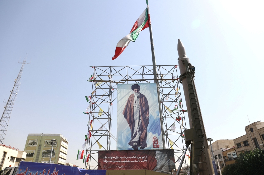 An Iranian missile system is displayed next to a banner with a picture of Iran's Supreme Leader Ayatollah Ali Khamenei and the late Lebanon's Hezbollah leader Hassan Nasrallah, in a street in Tehran, Iran, October 2, 2024. — Majid Asgaripour/Waba (West Asia News Agency) pic via Reuters 